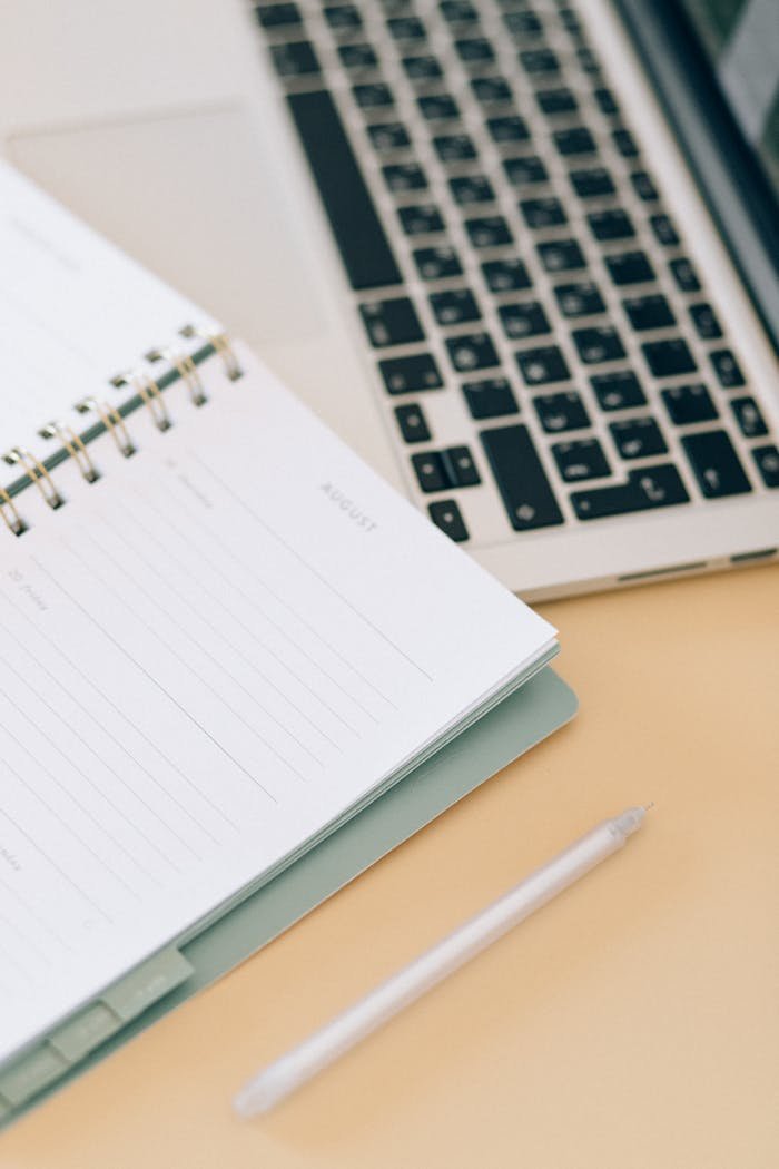 why-choose-us Open notebook next to a laptop and pen on a desk, ideal for business and planning.