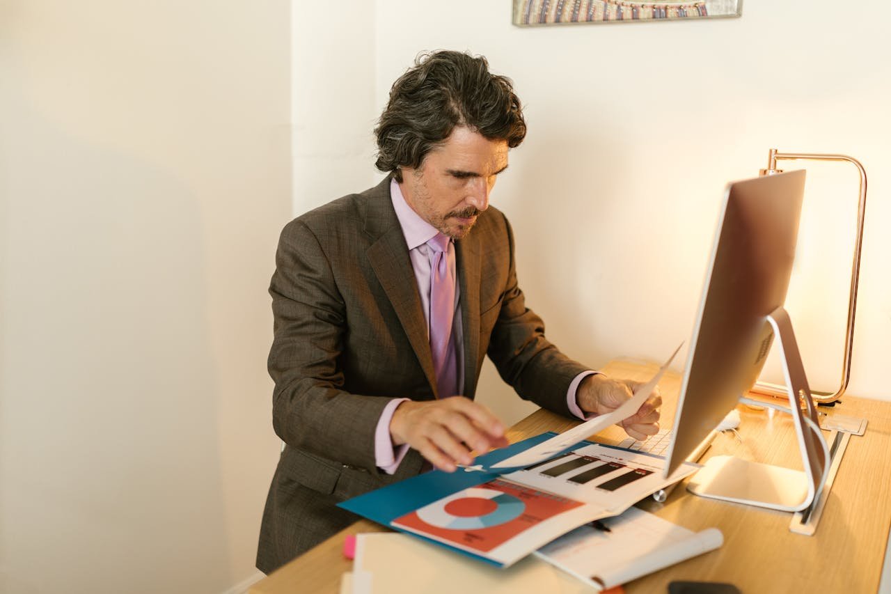 our-services-2 Businessman in suit reviewing financial documents in modern office space.